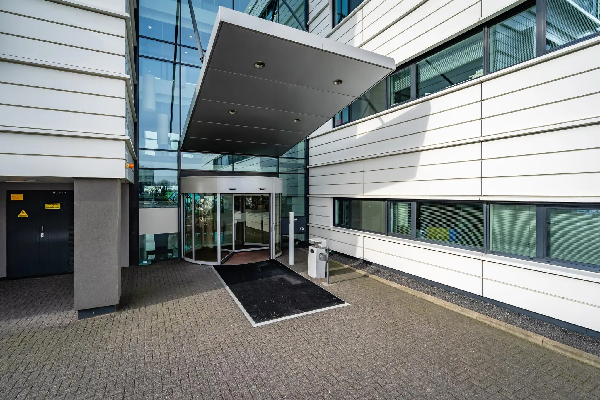 Ingang van een modern kantoorgebouw aan de Waalhaven O.Z. met een glazen gevel en draaideur.